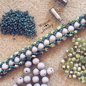 May include: A handcrafted beaded bracelet with light pink and teal beads, along with loose beads and a clasp. The bracelet is labeled "Wescott Jewelry."