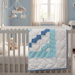 May include: A white crib with a blue and white heart-patterned quilt. A teddy bear and pillow are inside the crib. A mobile with clouds and stars hangs above. The room has light blue walls and a changing table.
