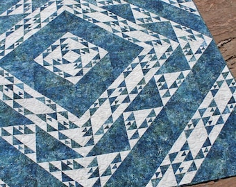 Könnte beinhalten: Eine blaue und weiße Steppdecke mit einem geometrischen Muster aus Dreiecken. Die Steppdecke ist aus Batikstoff gefertigt und hat einen weißen Hintergrund.