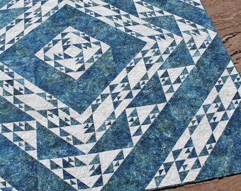 Könnte beinhalten: Eine blaue und weiße Steppdecke mit einem geometrischen Muster aus Dreiecken. Die Steppdecke ist aus Batikstoff gefertigt und hat einen weißen Hintergrund.