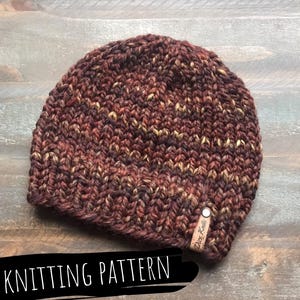 May include: A brown, beige, and black knitted beanie hat with a brown leather tag that says "Dice Knits".