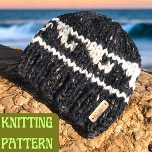 Op de afbeelding: Zwart-witte gebreide beanie met een wit streepdessin. De beanie heeft een bruin leren label met de tekst "DICI KNITS" erop.