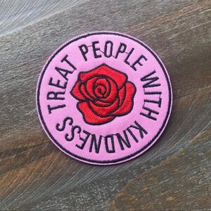 K&ouml;nnte beinhalten: Rosa gestickter Patch mit einer roten Rose und dem Text "Treat People With Kindness".