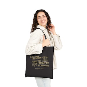 May include: Black tote bag with gold text reading "Flourish and Blotts Booksellers, Diagon Alley, London." The design includes stacked books and an open book. The bag is held by a person.