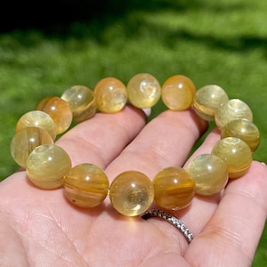 May include: A bracelet made of round, yellow and gold gemstone beads. The beads have a translucent, striated appearance.