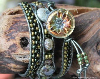 May include: Multi-strand bracelet with green, gold, and silver beads, leather cord, and a large, clear glass button with a flower design.