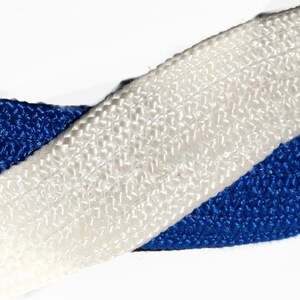 May include: Close-up of a woven ribbon featuring a vibrant blue and crisp white color scheme. The ribbon's texture is visible, showcasing a detailed weave pattern. The ribbon is likely used for crafting or decorative purposes.