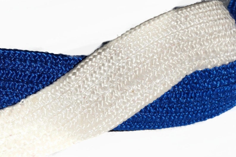 May include: Close-up of a woven ribbon featuring a vibrant blue and crisp white color scheme. The ribbon's texture is visible, showcasing a detailed weave pattern. The ribbon is likely used for crafting or decorative purposes.