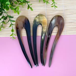Può includere: Quattro pettini per capelli in corno marrone e nero. I pettini hanno la forma di una U e hanno una finitura liscia e lucida.