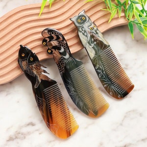 Puede incluir: Tres peines decorativos hechos de cuerno con intrincados tallados de un búho, un pájaro y dos peces. Los peines son marrones y negros con detalles dorados.