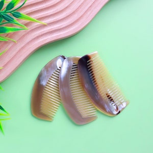 Puede incluir: Tres peines de cuerno de color marrón y beige, con forma curva y dientes finos.