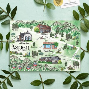 Könnte beinhalten: Eine Aquarellkarte von Aspen mit grünen Gebirgszügen, Pinien und roten Gondeln. Die Karte zeigt beschriftete Orte wie White House Tavern, Hotel Jerome, Paradise Bakery und The Little Nell mit weißen Straßenlinien auf grünem Grund.