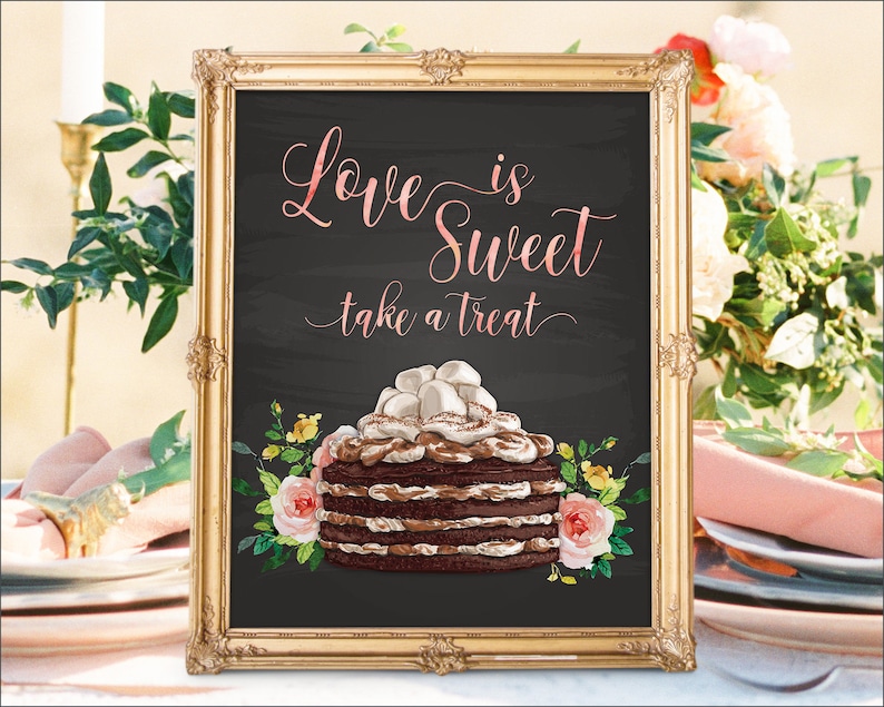 May include: A gold framed chalkboard sign with the text "Love is Sweet take a treat" in pink script. A chocolate cake with marshmallow frosting and floral accents is pictured below the text.