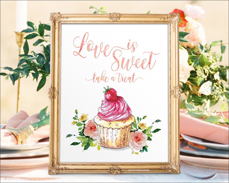 May include: A gold framed sign with the text "Love is Sweet, take a treat" in pink script. A pink and white cupcake with a strawberry on top is illustrated below the text.