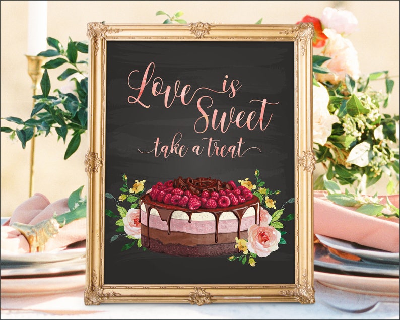 May include: A framed chalkboard sign with gold trim. The sign reads "Love is Sweet take a treat" in pink script. A watercolor cake with raspberries and chocolate sits below the text, surrounded by flowers. The sign is likely for a wedding or party.