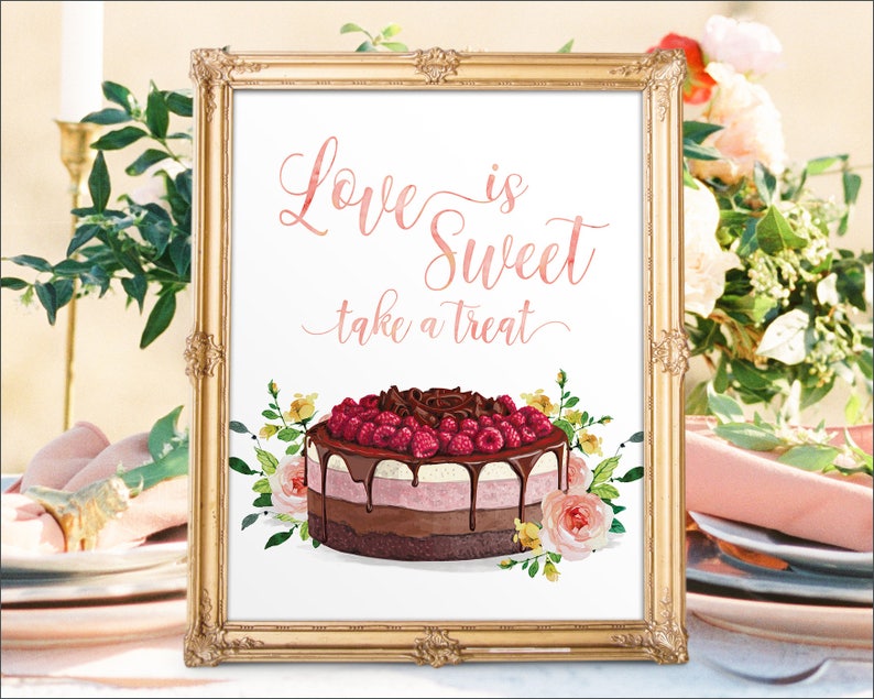 May include: A framed print with the text "Love is Sweet take a treat" in pink script. The image features a watercolor cake with chocolate ganache, raspberries, and floral accents. The frame is gold.