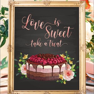 May include: A framed sign with the text "Love is Sweet take a treat" in a cursive font. The sign features a multi-layered cake with raspberries and chocolate, surrounded by floral accents. The frame is gold.