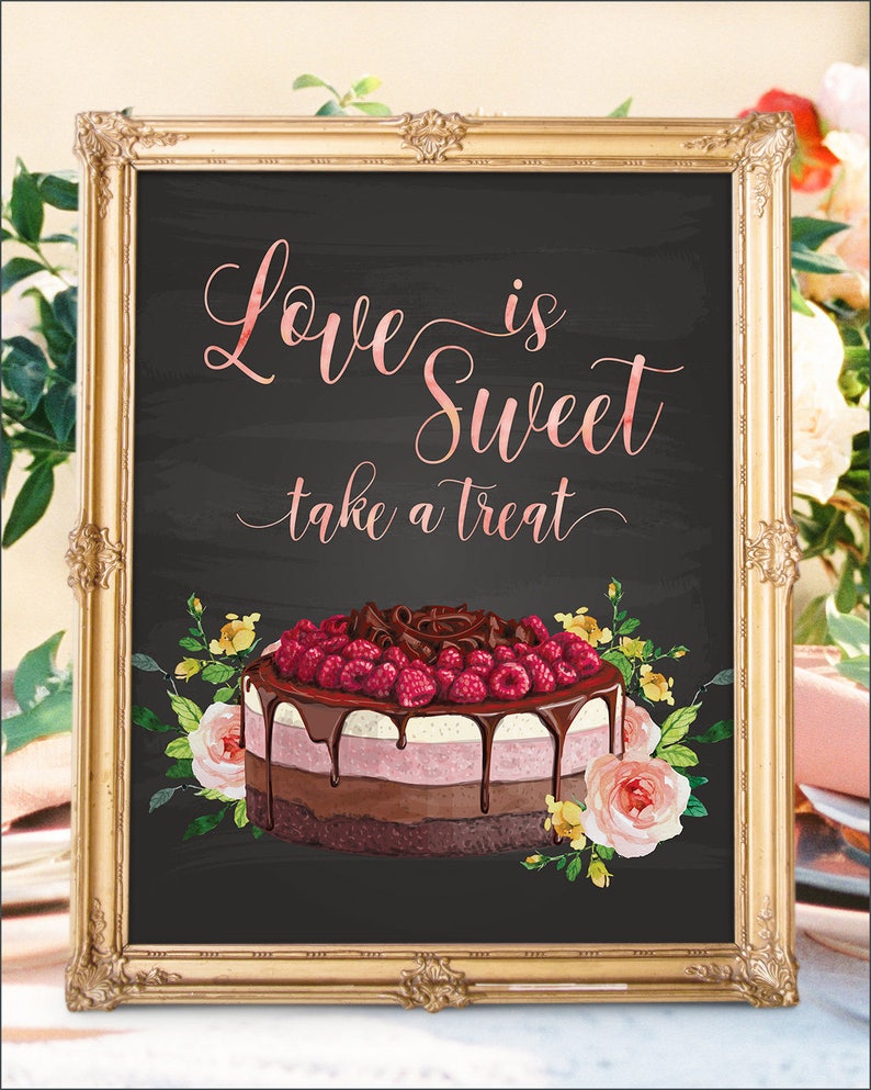 May include: A framed sign with the text "Love is Sweet take a treat" in a cursive font. The sign features a multi-layered cake with raspberries and chocolate, surrounded by floral accents. The frame is gold.