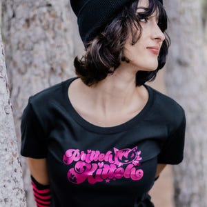 May include: A woman wearing a black beanie with a pink cat graphic and a black t-shirt with a pink "British Kitten" graphic.