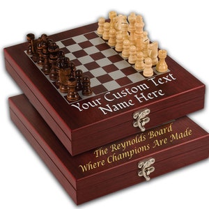 May include: A mahogany wood chess set with a folding board and a personalized inscription that reads "Your Custom Text Name Here". The bottom of the box reads "The Reynolds Board Where Champions Are Made".