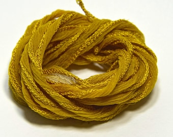 May include: A spool of bright yellow silk ribbon, perfect for crafting and adding a touch of elegance to projects.