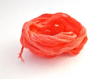 May include: A coiled length of vibrant neon orange ribbon featuring a crinkled, textured surface and delicate, frayed edges. The ribbon is wound into a loose, circular shape, showcasing its lightweight, semi-sheer fabric and bright color.