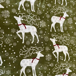 May include: Green fabric with a repeating pattern of white reindeer with decorative antlers and red neck ribbons. The reindeer are interspersed with snowflakes and white dots. The fabric has a festive, holiday theme.