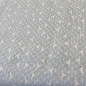 May include: Light blue fabric with a repeating pattern of white triangles and a grid design. The triangles are evenly spaced and create a geometric pattern across the fabric. The fabric has a soft, matte finish.
