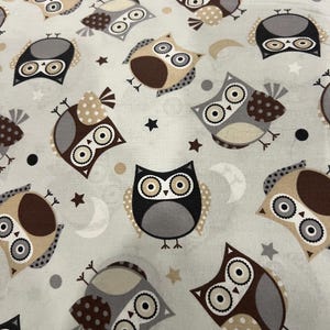 May include: Light gray fabric with a repeating pattern of cartoon owls in various colors, including brown, gray, and beige. The owls are interspersed with stars, moons, and dots.