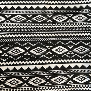 May include: Black and white patterned fabric with a geometric design. The pattern features repeating shapes, including diamonds, triangles, and zigzags, creating a bold, symmetrical design. The fabric is likely used for clothing or home decor.