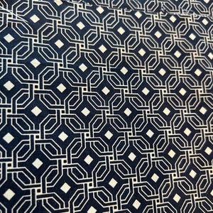 May include: Close-up of a fabric with a repeating geometric pattern. The design features interconnected white lines forming octagons and diamonds against a dark navy blue background. The fabric has a textured appearance.