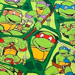 May include: Green fabric featuring multiple cartoon images of the Teenage Mutant Ninja Turtles. Each turtle is depicted with a different colored mask: orange, purple, red, and blue. The turtles are in action poses, some holding weapons.