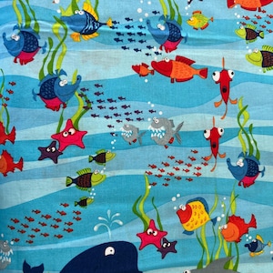 May include: A vibrant fabric featuring an underwater scene with cartoon fish, starfish, and a whale. The design includes various colorful fish, seaweed, and schools of small fish against a blue, wavy background. The fabric is suitable for children's projects.