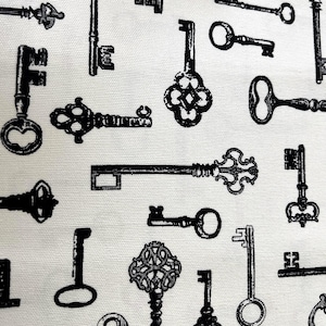 May include: A collection of black antique keys in various shapes and sizes are printed on a white background. The keys have ornate designs and are arranged in a random pattern. The image is a close-up of a fabric or paper.