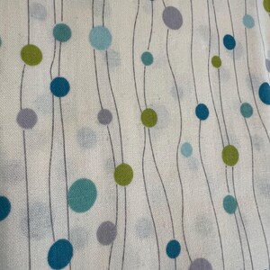 May include: Close-up of a white fabric with a repeating pattern of teal, blue, green, and purple circles connected by wavy gray lines. The circles vary in size and are evenly spaced across the fabric.
