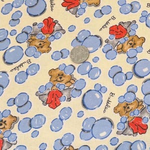 May include: A cream-colored fabric featuring a repeating pattern of brown teddy bears in gray bathtubs with blue bubbles and red towels. The word Bubbles is printed in black script. A silver US quarter coin is placed in the center for scale.