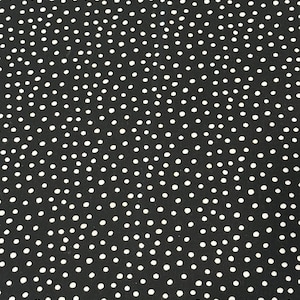 May include: A black fabric featuring a dense, repeating pattern of small, irregular white dots scattered across the surface. The dots vary slightly in size and shape, creating a hand-drawn appearance against the solid black background.