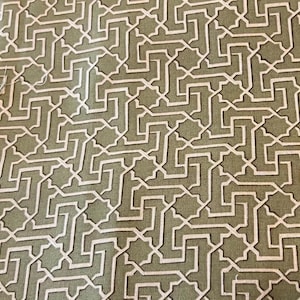 May include: Close-up of a fabric with a repeating geometric pattern. The design features a series of interconnected, angular shapes in white against a muted green background. The pattern creates a maze-like effect, suitable for various textile applications.