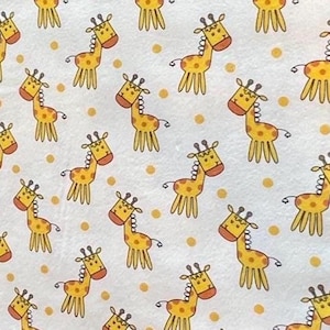 May include: White fabric with a repeating pattern of cartoon giraffes in yellow and orange. The giraffes have brown spots and are interspersed with yellow polka dots. The design is suitable for children's items.