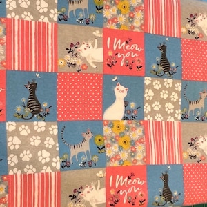 May include: A patchwork fabric featuring cat-themed squares. The squares display various designs, including cats, paw prints, floral patterns, and the phrase "I Meow You." Colors include blue, pink, gray, and white.