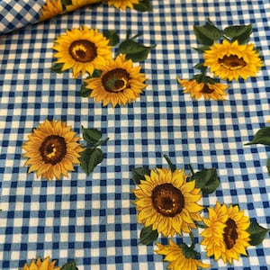 May include: Blue and white gingham fabric with a pattern of yellow sunflowers. The sunflowers have brown centers and green leaves. The fabric is suitable for various craft and sewing projects.
