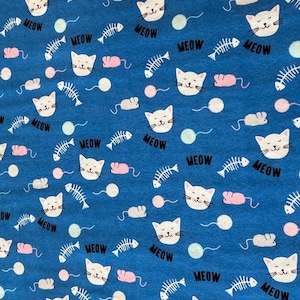 May include: Blue fabric with a repeating pattern of white cat faces, fish bones, pink mice, and yarn balls. The word "MEOW" is printed in black around the cat faces. This fabric is suitable for various sewing projects.