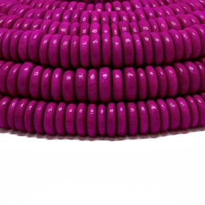 May include: A close-up of a pile of bright pink wooden beads. The beads are round and have a smooth, polished finish.