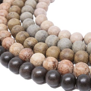 May include: A close-up of a wooden bead necklace with a gradient of colors, starting with dark brown and transitioning to light brown. The beads are round and smooth, and the necklace is made of multiple strands.