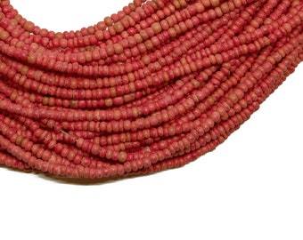 May include: Close-up of a collection of small, round, coral-colored beads. The beads are strung together, creating a layered effect. The beads have a slightly textured surface and are arranged against a white background.