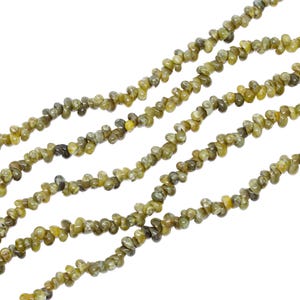 May include: Strands of olive-green gemstone beads. The beads are small, irregular in shape, and strung together. The color varies from light yellow-green to darker olive tones. Ideal for jewelry making.