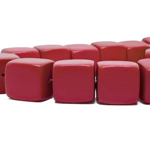 Puede incluir: Una hebra de cuentas cuadradas rojas. Las cuentas están hechas de un material liso y pulido y tienen un borde ligeramente redondeado.