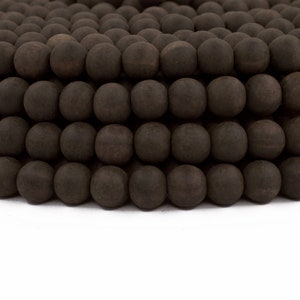 May include: Close-up of a collection of dark brown wooden beads. The beads are spherical and arranged in neat rows, creating a textured surface. The beads are likely for jewelry making or craft projects.