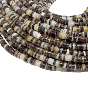 Puede incluir: Primer plano de un hilo enrollado de pequeñas cuentas planas. Las cuentas son una mezcla de negro, blanco y marrón. Las cuentas son uniformes en tamaño y forma, creando una superficie texturizada. Estas cuentas probablemente se utilizan para hacer joyas.