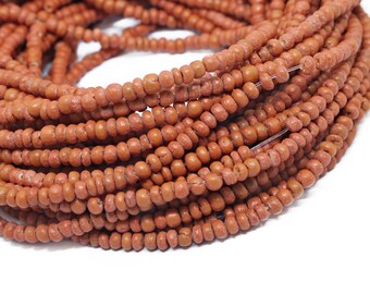 May include: A strand of terracotta-colored seed beads. The beads are small and round, and they are strung together on a thin wire.